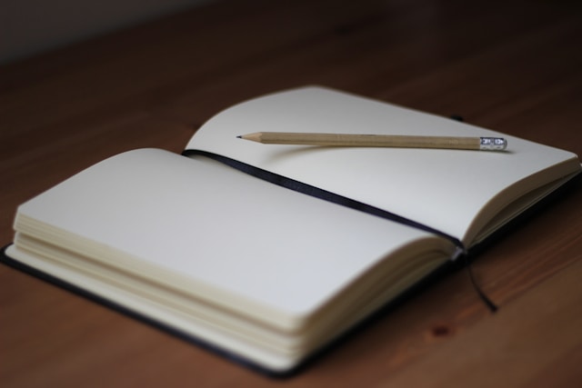 Een opengeslagen notitieboek met een potlood op een houten tafel